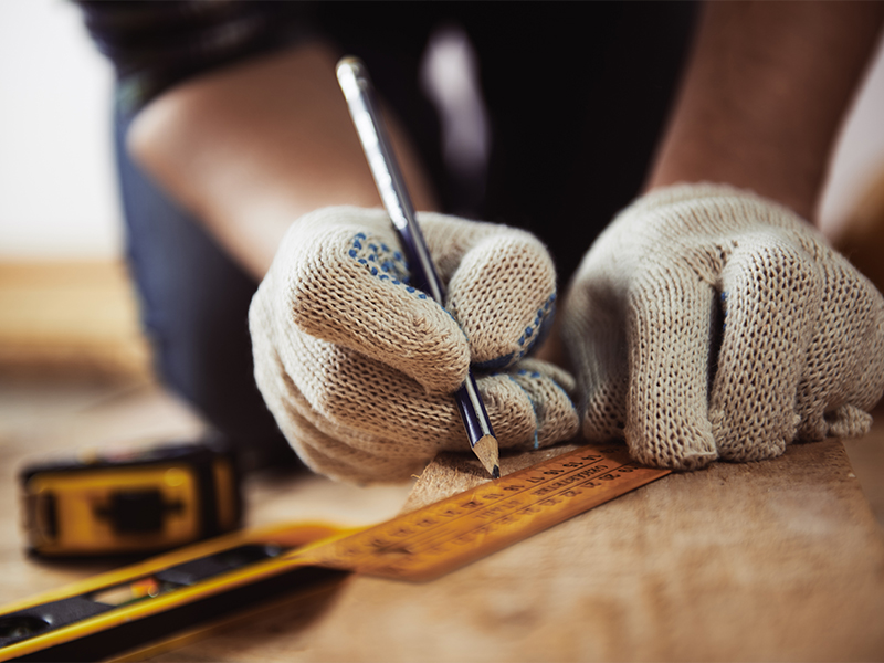 Craftsman measuring with a ruler and protective gloves